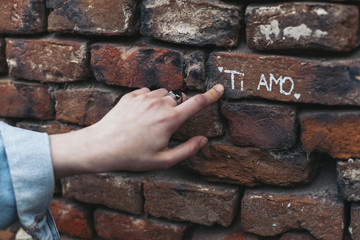 Cropped hand of woman showing text on brick wall
