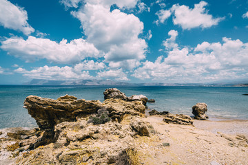 Panoramic view of rocks and beach with sky and clouds in Crete, Greece. Amazing scenery with crystal clear water and the rock formation against a deep blue sky during Summer period. Greece, Europe