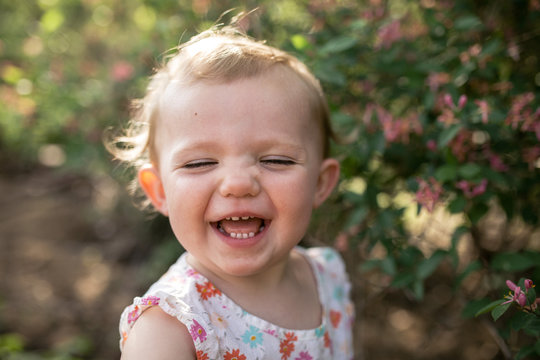 Close-up of happy baby girl standing against plants at park