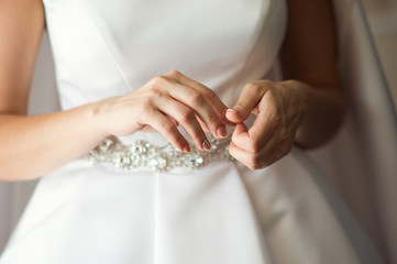 The hands of bride in white wedding dress