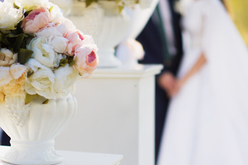 The bride and the groom on the backround. Floral decoration of wedding outdoor ceremony. Summer...