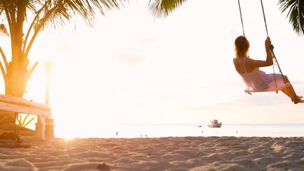 Happy woman on beach vacation holidays, slow motion footage of girl on rope swing crossing the sun, travel destination leisure concept