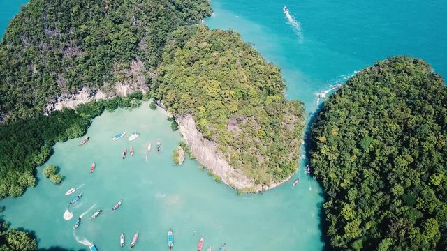 Beach vacation holidays destination, drone aerial footage of tropical paradise island touristic laguna near Krabi, Thailand with traditional Thai longtail boats
