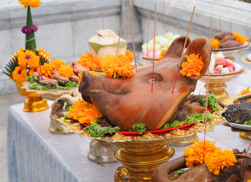 Boiled pig's heads decorated with flowers sacrificial offering in worship. Bangkok, Thailand.
