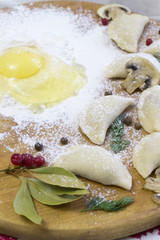 Traditional Russian food dumplings or vareniki, dough with meat or other stuffing, with flour and egg served on a table with sour cream, mushrooms and fresh vegetables, garlic sauce. traditional