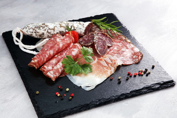 Food tray with delicious salami, ham,  fresh sausages and herbs. Meat platter with selection