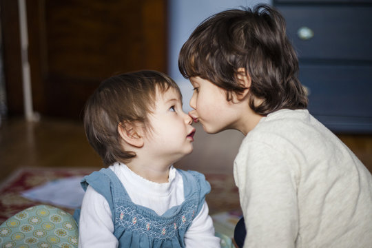 Close-up of brother kissing cute sister on nose while sitting at home