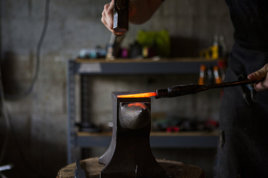 Blacksmith forging knife on anvil in workshop