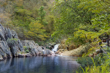 Naklejka na ściany i meble lake with waterfall in the middle of rocks