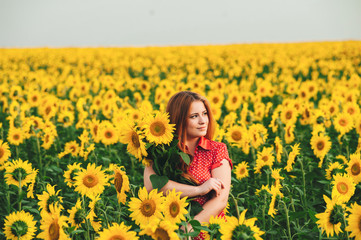 Fototapeta premium Beautiful girl in a huge yellow field of sunflowers.