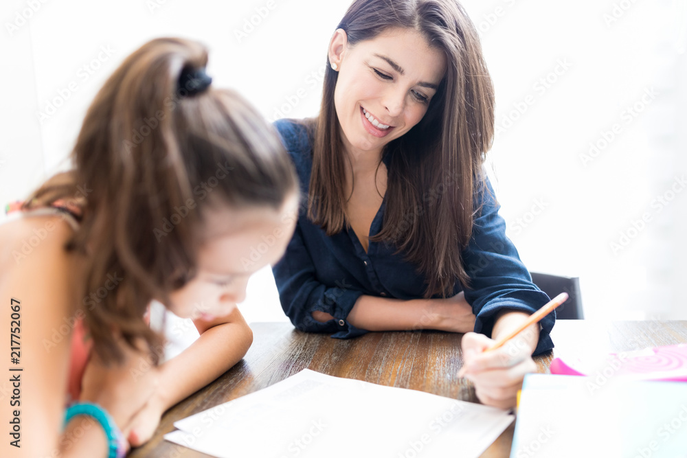 Wall mural teacher smiling while teaching girl at home