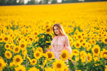 Fototapeta premium Beautiful girl in a huge yellow field of sunflowers.
