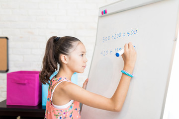 Girl Solving Math's Sums On Flip Chart At Home