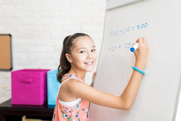 Cute Female Student Solving Sums On Flip Chart At Home