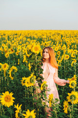 Naklejka na ściany i meble Beautiful girl in a huge yellow field of sunflowers.