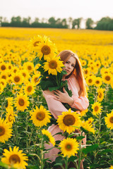 Beautiful girl in a huge yellow field of sunflowers.