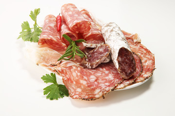 Food tray with delicious salami, ham,  fresh sausages and herbs. Meat platter with selection