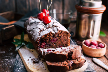 Chocolate pie with cherries on a dark wooden background, powdered sugar powder, cup with coffee, dessert, baked goods