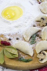 Traditional Russian food dumplings or vareniki, dough with meat or other stuffing, with flour and egg served on a table with sour cream, mushrooms and fresh vegetables, garlic sauce. traditional