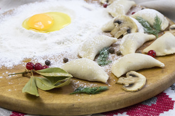 Traditional Russian food dumplings or vareniki, dough with meat or other stuffing, with flour and egg served on a table with sour cream, mushrooms and fresh vegetables, garlic sauce. traditional