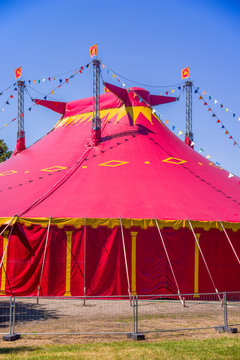 Circus tent detail. Red circus tent in green built in a green field against a blue sky.