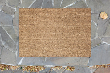 Blank doormat before the door in the hall. Mat on ceramic floor, flowers and red shoes. Welcome...