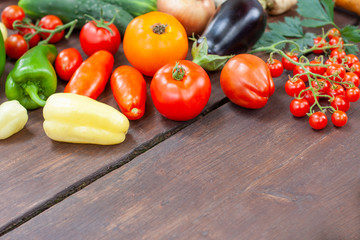 Colourful variety of fresh home grown vegetables from an organic garden on a wooden surface. Tomato, green and yellow bell peppers, carrot, parsley, onion, garlic, potato, eggplant and zucchini.