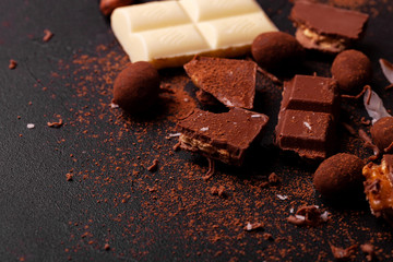 Сhocolate pieces and cocoa powder on marble. The chunks of chocolate over dark background