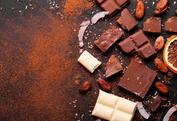 Сhocolate pieces and cocoa powder on marble. The chunks of chocolate over dark background