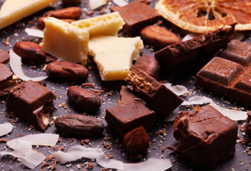 Сhocolate pieces and cocoa powder on marble. The chunks of chocolate over dark background