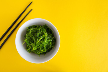 Salad with seaweed and sesame in the white plate on the  yellow  background.Top view.Copy space.