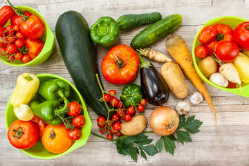Colourful variety of fresh home grown vegetables from an organic garden on a wooden surface. Tomato, green and yellow bell peppers, carrot, parsley, onion, garlic, potato, eggplant and zucchini.