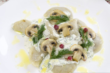 Traditional Russian food dumplings or vareniki, dough with meat or other stuffing, with flour and egg served on a table with sour cream, mushrooms and fresh vegetables, garlic sauce. traditional