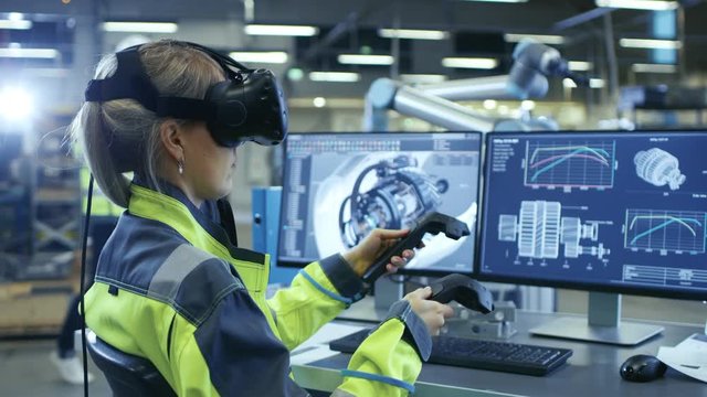 Factory: Female Industrial Engineer Wearing Virtual Reality Headset and Holding Controllers, She Uses VR technology for Industrial Design, Development and Prototyping in CAD Software.