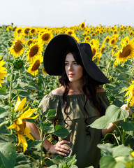 Portrait of the beautiful girl with a sunflowers. Beautiful sweet girl in dress and hat walking on a field of sunflowers, smiling. Nature, summer holidays, vacation