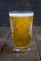 lager draft beer in a glass on dark wooden background