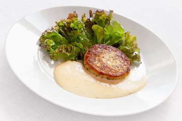 fried cabbage patty on lettuce leafs with adjika based sauce