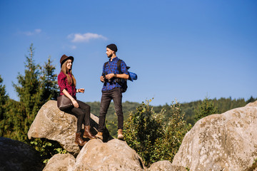 A traveler couple standing together on the rocks at the mountains over the blue sky background