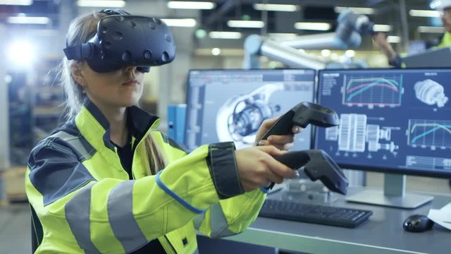 Factory: Female Industrial Engineer Wearing Virtual Reality Headset and Holding Controllers, She Uses VR technology for Industrial Design, Development and Prototyping in CAD Software.