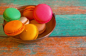 Macarons in a metal cup on an old wooden background