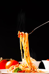 Hot spaghetti with tomato sauce in white plate,  food stylish action with black background, pull...