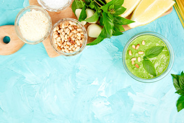 Homemade pesto sauce in glass jar with ingredients.