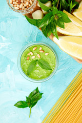 Homemade pesto sauce in glass jar with ingredients.