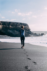 Lonely barefoot woman walking on ocean beach
