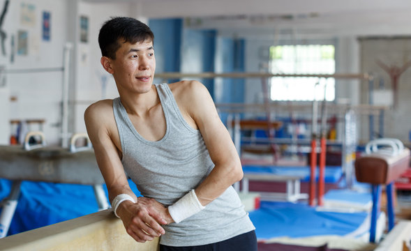 Positive young man asian acrobat posing  at modern sport gym