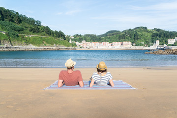 Pareja de enamorados pasando un día soleado en la playa de Saturraran en Euskadi, España