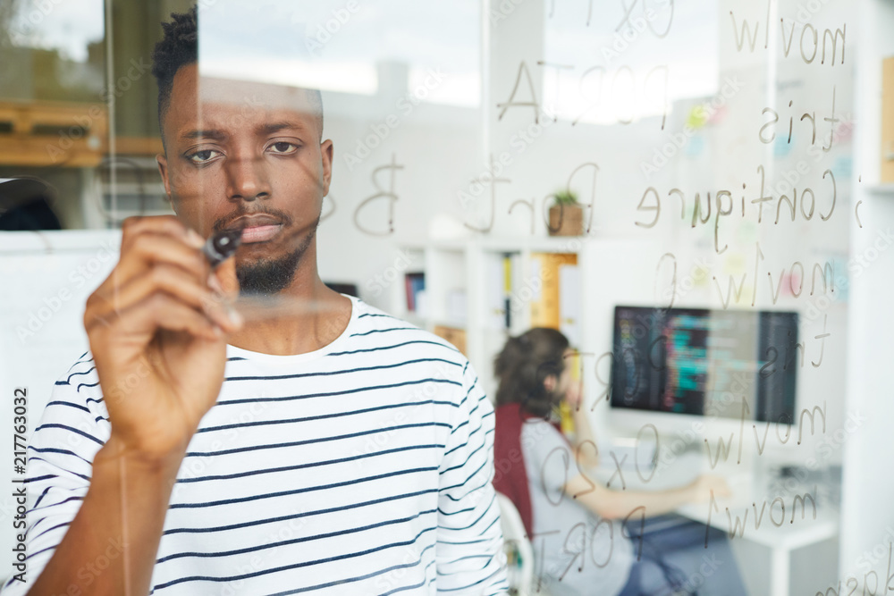 Sticker serious guy with highlighter writing down software codes on board while working in office