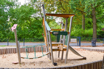 Climbing frame with equipment out of wooden elements on a public playground in Berlin.