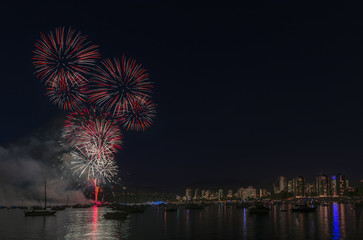 colorful flashes of night fireworks over the ocean with floating yachts