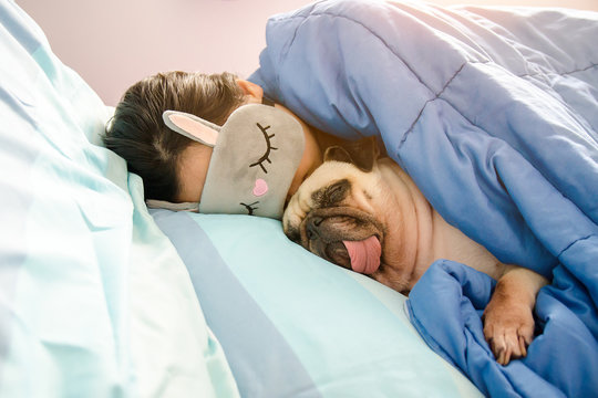 Sweet asian woman with mask and cute puppy pug dog is sleeping rest in the bed.